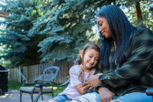 live-live nanny and small girl sitting on bench in back yardYoung woman and small girl sitting on bench in back yard