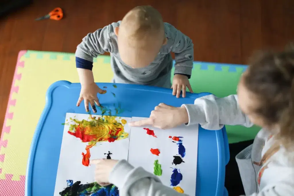 nanny playing with child and paints